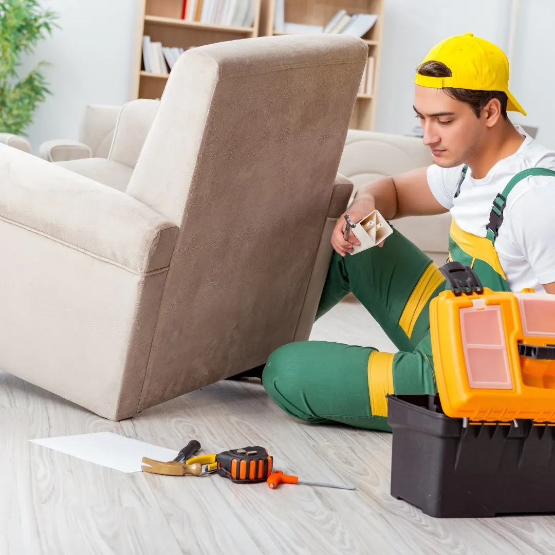 Handyman working on an armchair with a toolbox nearby