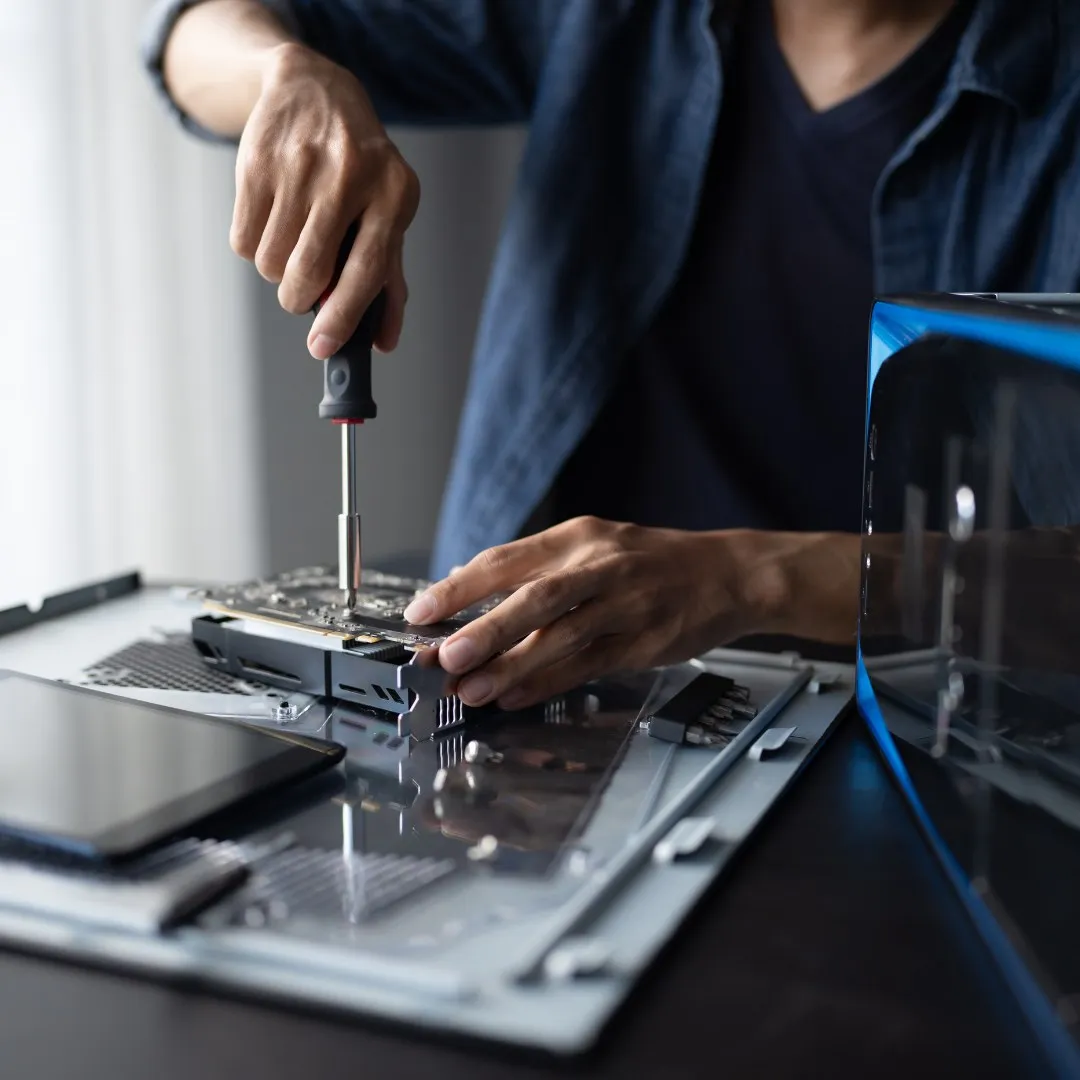 Hands using a screwdriver on an open laptop