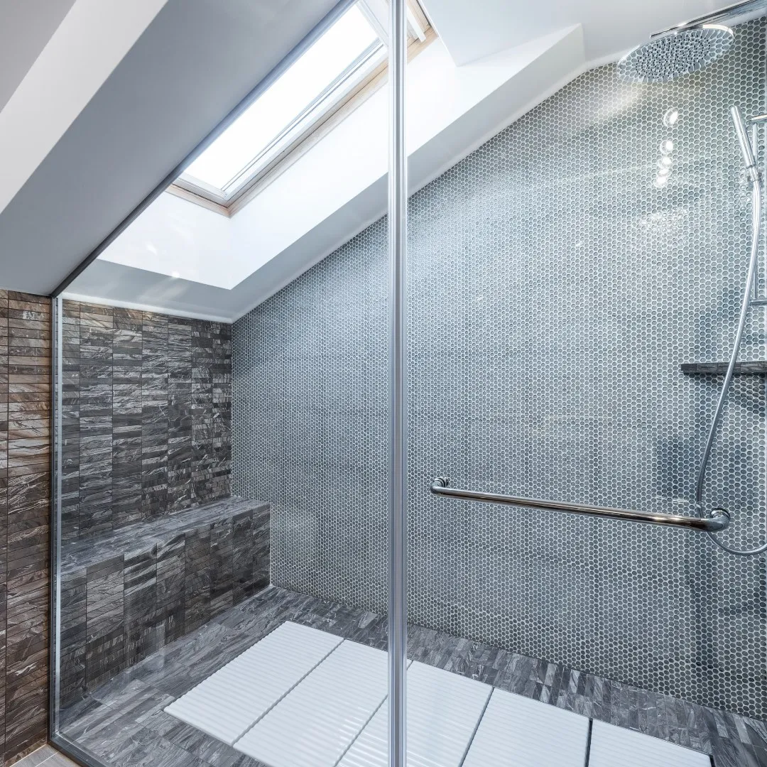 Walk-in shower with a glass panel and grab bar