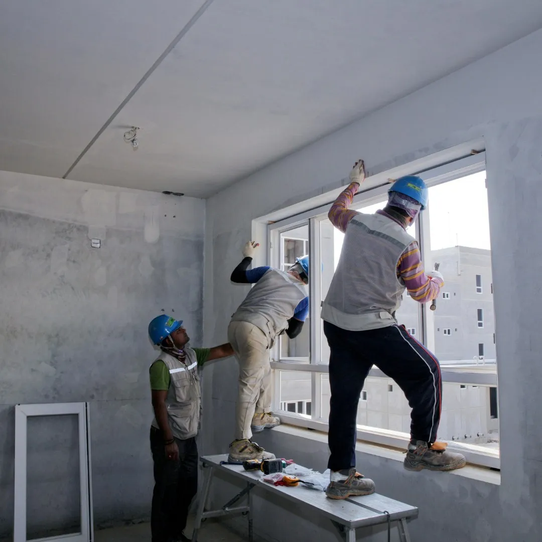 Team working on large windows in an unfinished room