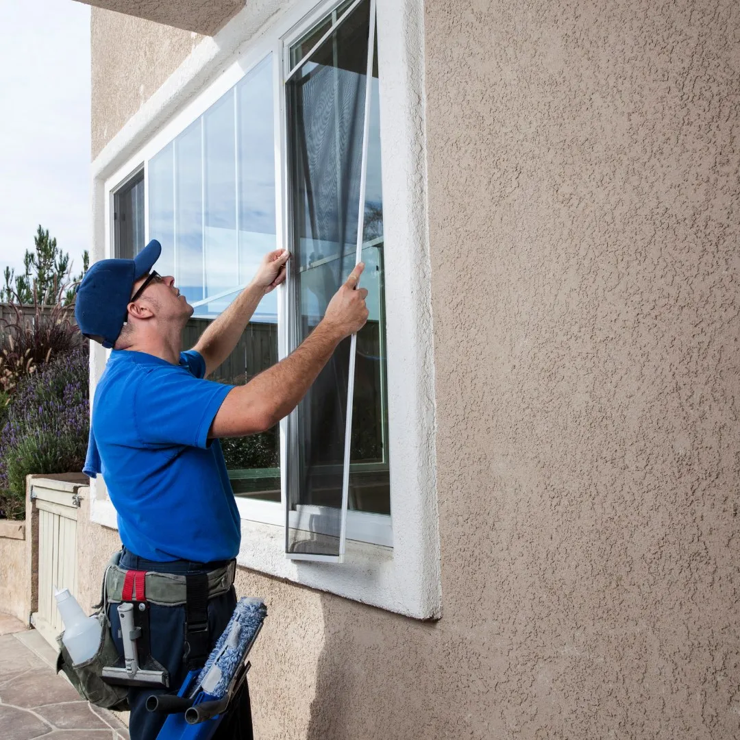 Handyman fitting a window screen on a home